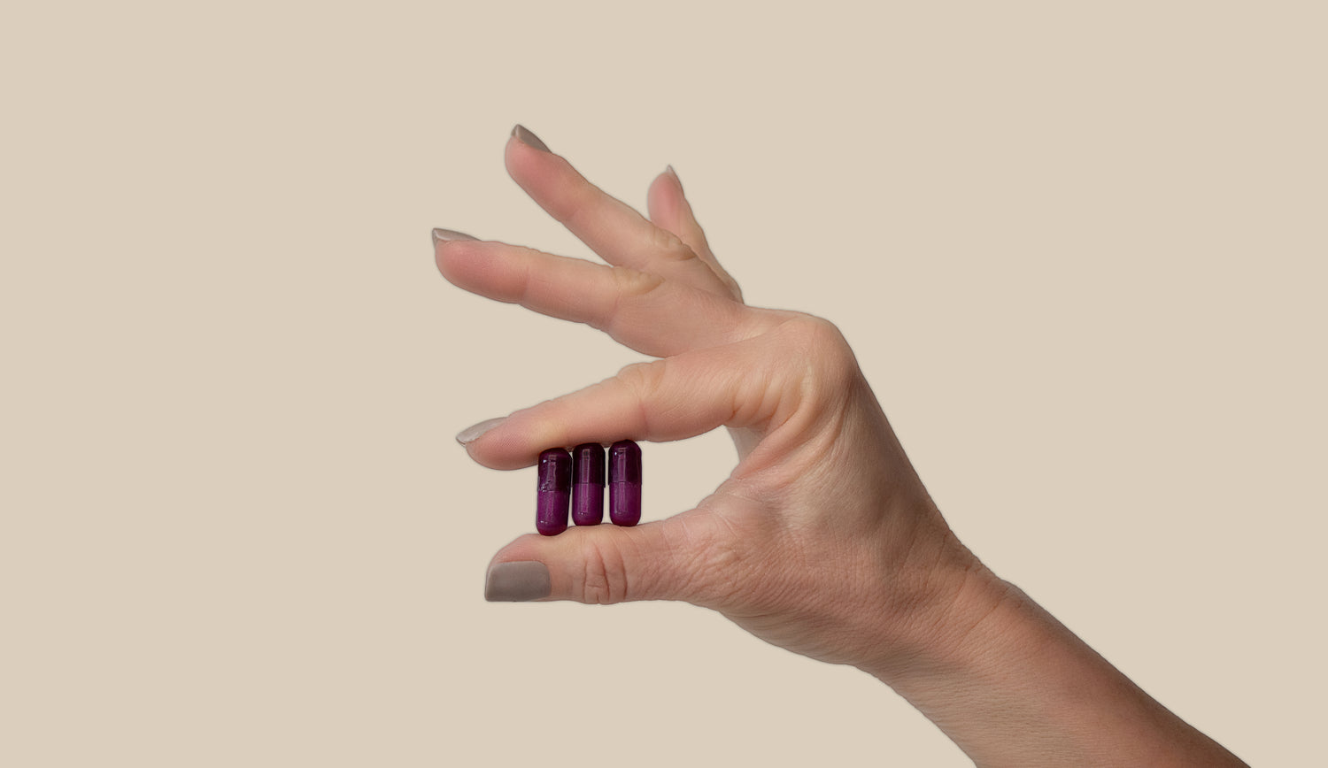 A hand holding 3 Nutrilinq Essentials Capsules