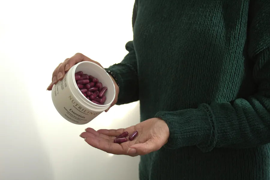 Essentials capsules poured from the jar into a hand