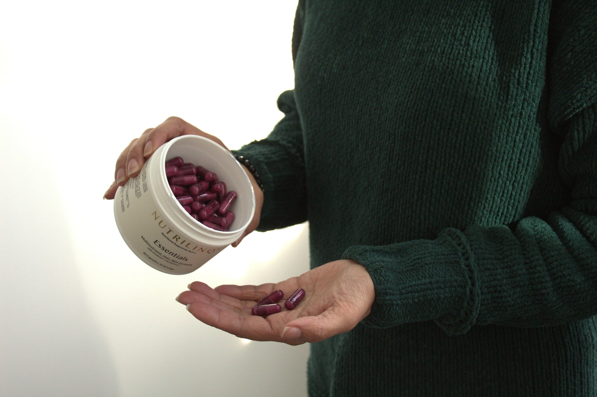 A woman taking her daily three Nutrilinq Essentials Capsules for Hair, Skin and Nail support while on GLP-1 Drugs.